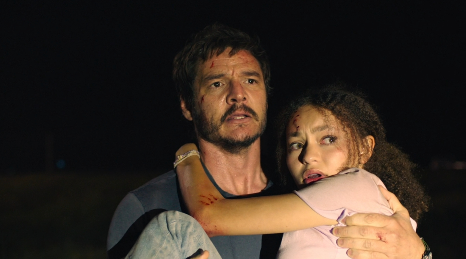 Joel holds his daughter Sarah as they are caught in the glare of a flashlight in The Last of Us (2023).