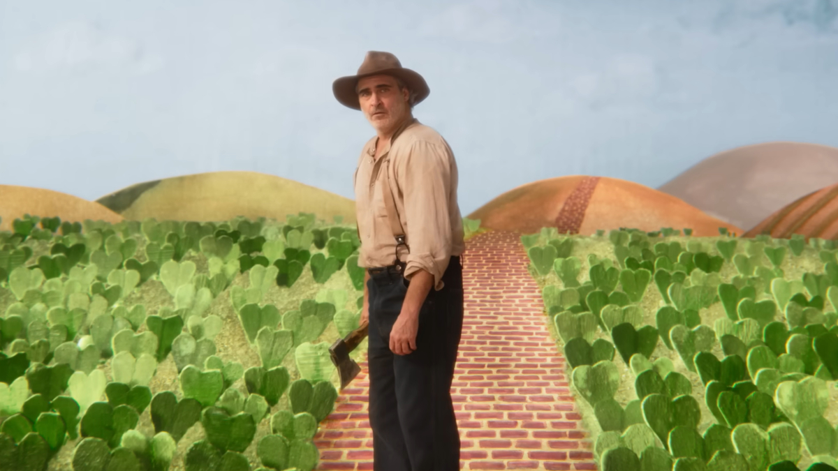 Joaquin Phoenix is Beau, standing in a field of cacti in Beau is Afraid (2023).