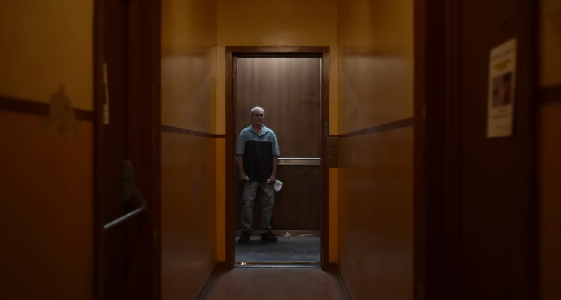 Joaquin Phoenix stands in an elevator in Beau is Afraid (2023).