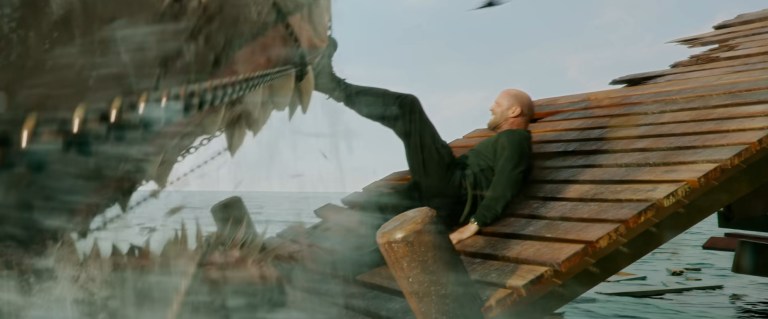 Jason Statham holds a shark back with his foot in The Meg 2: The Trench (2023).