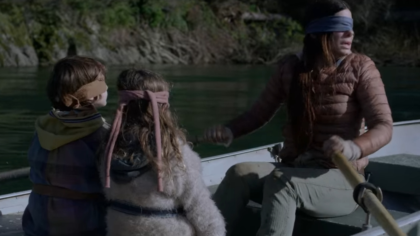 Sandra Bullock in Bird Box (2018) rowing a boat with two kids.
