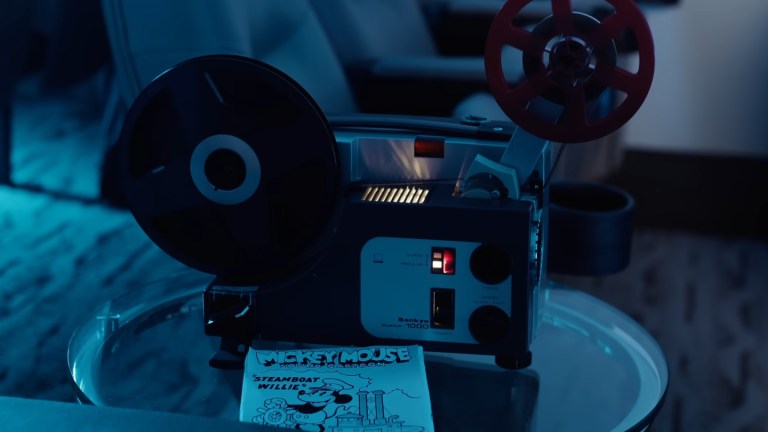 A film projector with Steamboat Willie artwork placed beside it.