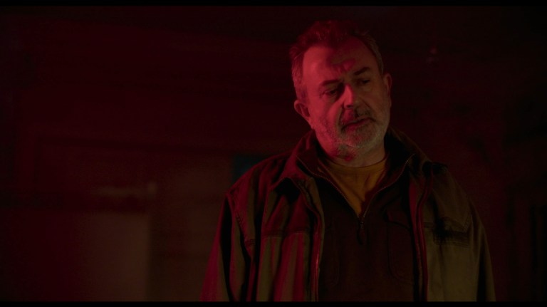Breezeblock standing in a red light in All You Need is Death (2023).