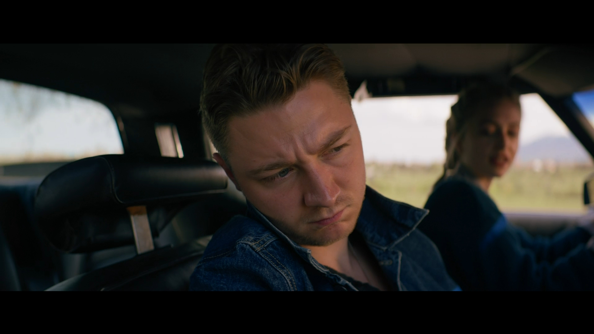 Rick stares out of a car window in Refuge (2023).