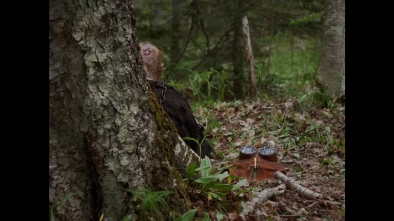 Johnny sits behind a tree in In a Violent Nature (2024).