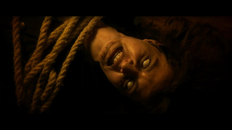 A witch with white eyes curses the crew of a pirate ship in Ship of the Damned (2024).