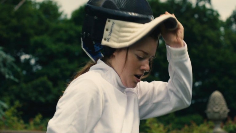 Lily removes her fencing helmet in Wild Eyed and Wicked (2023).