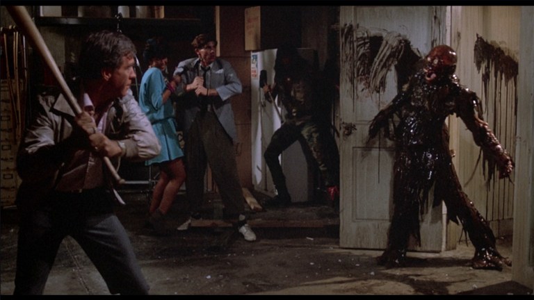 Burt prepares to knock Tarman's head off in The Return of the Living Dead (1985).