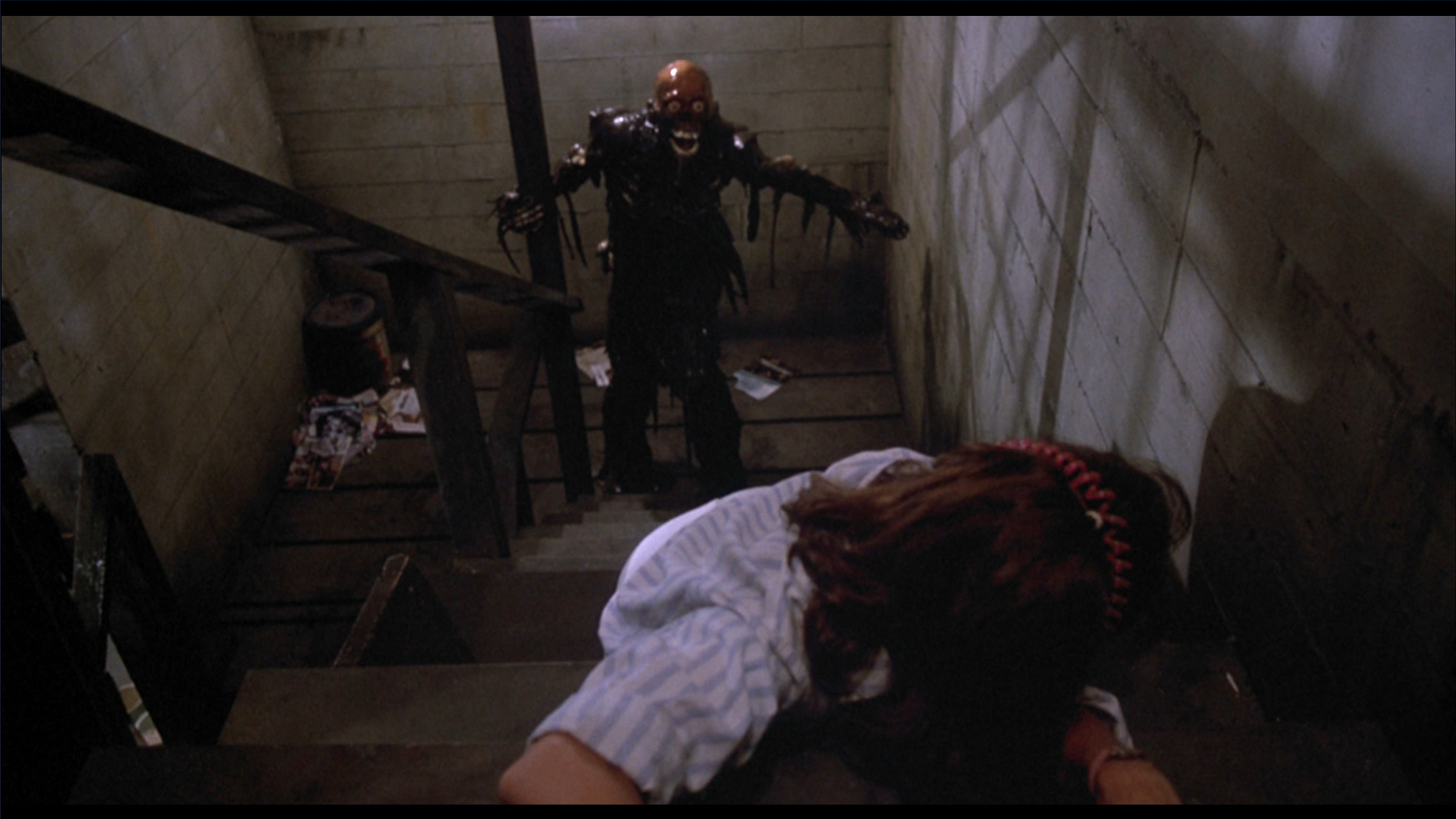 The Tarman climbs stairs towards Tina in The Return of the Living Dead (1985).