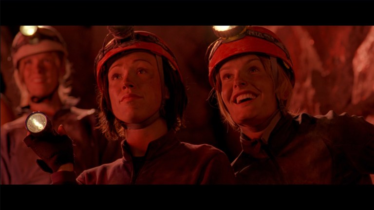 Beth looks smug as Rebecca smiles in The Descent (2005).