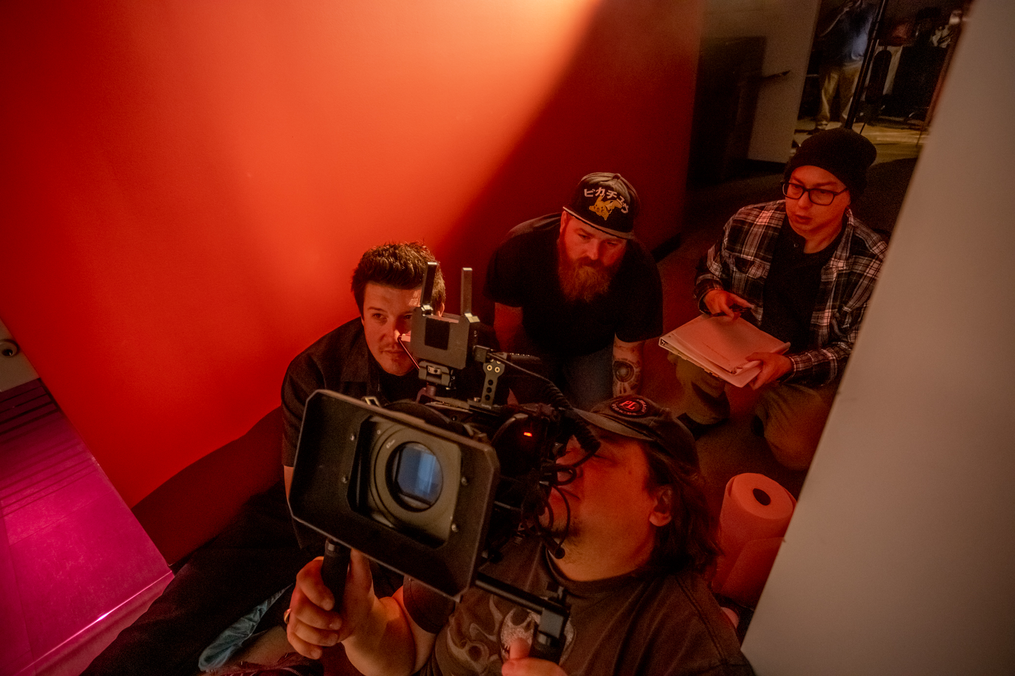 A behind the scenes photo of P.J. Starks with a cameraman and other crew members crouched in a hallway.