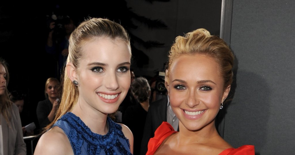 Emma Roberts in a blue dress and Hayden Panettiere in a red dress smiling together on the Scream 4 premiere red carpet.